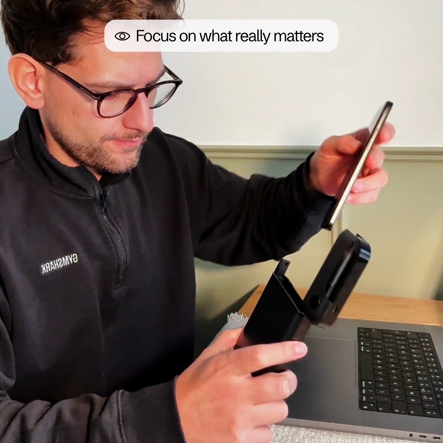 A man slides his phone into the Lockbox to focus at his laptop